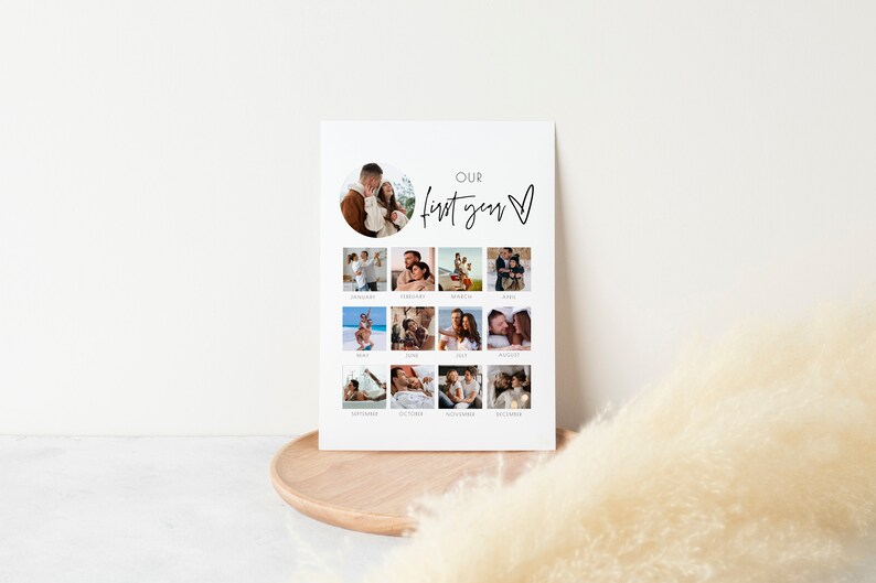 Puede incluir: Una impresi&oacute;n fotogr&aacute;fica blanca con un collage de doce im&aacute;genes, una por cada mes, y una imagen central. El texto "Our first year" est&aacute; escrito en un estilo manuscrito. La impresi&oacute;n se muestra en una bandeja de madera.