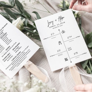 Pode incluir: Dois programas de leques de casamento brancos com texto preto e alças de fita. Um leque lista os convidados do casamento, o outro uma linha do tempo para o dia. O texto inclui os nomes dos noivos e a data.