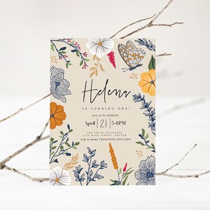 Puede incluir: Una tarjeta de invitaci&oacute;n beige con un dise&ntilde;o floral con mariposas, flores y hojas en tonos azules, amarillos, naranjas, rojos y verdes. El texto de la tarjeta dice "&iexcl;Helen cumple un a&ntilde;o! &Uacute;nase a nosotros para celebrar el 21 de abril | 17:00-18:00 The Smith Residence 1234 Main Street, Denver rsvp to emma (000)000.000.000"