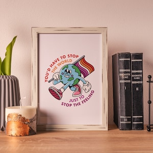 May include: A white framed print with a cartoon illustration of the Earth holding a rainbow flag and running. The text reads "You'd have to stop the world just to stop the feeling."