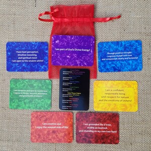 May include: Set of 7 affirmation cards with colorful backgrounds and inspirational messages. Each card features a different affirmation related to personal growth and well-being. The cards are laid out on a burlap surface.