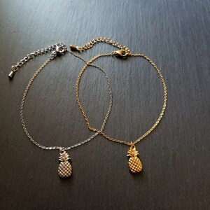 May include: Two delicate anklets with pineapple charms. One anklet is silver and the other is gold.