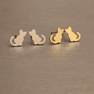 May include: A pair of cat-shaped stud earrings, one silver and one gold.