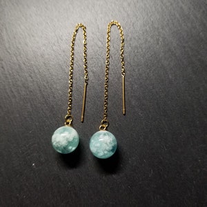 Peut inclure: Une paire de boucles d'oreilles pendantes dorées avec des perles d'agate bleues et blanches.