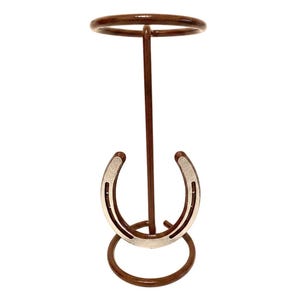 May include: A brown metal horseshoe ring toss game. The game features a circular top and base, with a vertical support and a horseshoe-shaped target. The horseshoe target is silver and brown.