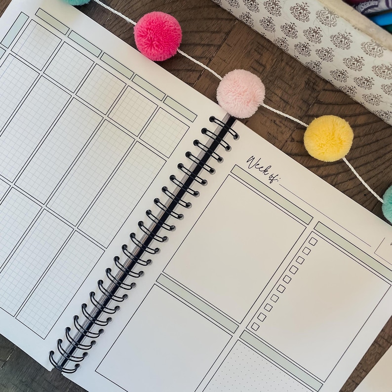 May include: A white planner with a black spiral binding. The planner has a gridded section on the left side and a blank section on the right side. The right side has the text "Week of:" at the top.