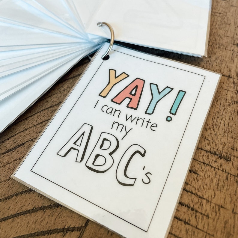 May include: A white card with a black border and colorful text that reads "YAY! I can write my ABC's". The letters are in a playful, hand-drawn style.