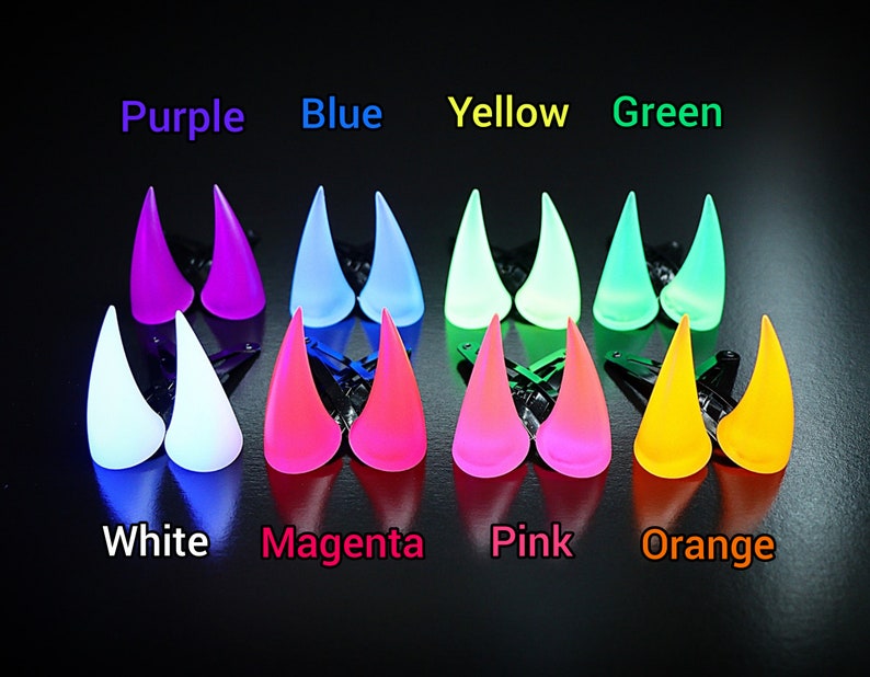 May include: A collection of glowing, horn-shaped hair clips in various colors, including purple, blue, yellow, and green. The image also displays white, magenta, pink, and orange clips. The text above each color indicates the color of the clip.