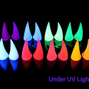 May include: A collection of glowing, horn-shaped objects in various colors, including purple, blue, green, red, and yellow, are arranged against a black background. The text "Under UV Light" is visible at the bottom.