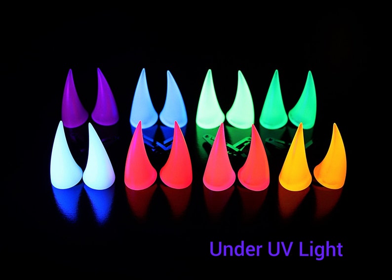 May include: A collection of glowing, horn-shaped objects in various colors, including purple, blue, green, red, and yellow, are arranged against a black background. The text "Under UV Light" is visible at the bottom.