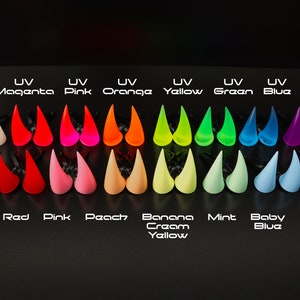 May include: A collection of UV-reactive horns in various colors, including white, magenta, pink, orange, yellow, green, blue, and purple. Each color is labeled with its name. The bottom row features additional colors: black, red, pink, peach, banana cream yellow, mint, baby blue, and lavender.