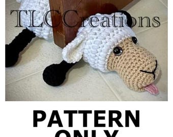 May include: Crocheted white sheep doorstop with black legs and a pink tongue sticking out. The doorstop is lying on a tiled floor. The text "TLC Creations" is visible in the background.