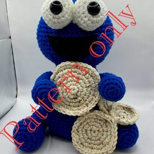 May include: A handmade blue crochet Cookie Monster plush toy with large white eyes and a wide black mouth. The toy is holding several crochet cookies. The words "Pattern Only" are printed on the image.