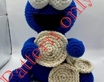 Op de afbeelding: Een handgemaakt blauw Cookie Monster pluche speelgoed van gehaakt materiaal met grote witte ogen en een brede zwarte mond. Het speelgoed houdt verschillende gehaakte koekjes vast. De woorden "Pattern Only" staan op de afbeelding.