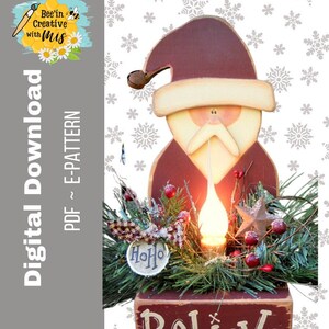 May include: A wooden Santa Claus cutout with a red hat and beard, holding a light bulb. The Santa is surrounded by greenery and a sign that reads "Believe".