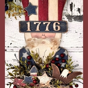 May include: A wooden patriotic Uncle Sam figurine with a red, white, and blue top hat, a white beard, and a blue and white striped shirt. The figurine is holding a basket with red berries, green leaves, and a wooden eagle. The basket is decorated with stars and the number 1776.
