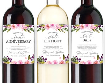 May include: Six wine bottles with personalized labels featuring floral designs and text that reads "Cheers to your first..." followed by different milestones, such as "Newlyweds", "Wedding Night", "Anniversary", "Big Fight", "Baby", and "Christmas".