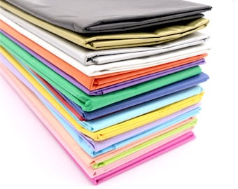 May include: A stack of colorful tissue paper in various shades of blue, green, pink, yellow, orange, and white. The tissue paper is folded and stacked neatly, with the top layer being a dark gray color.