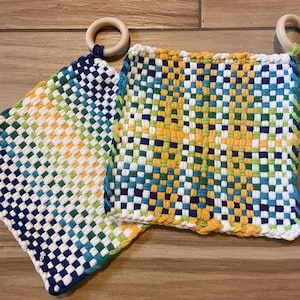 Peut inclure: Deux dessous de plat tissés avec des anneaux en bois. L'un présente un dégradé de couleurs bleu, vert, jaune et blanc. L'autre a un motif similaire avec un mélange de bleu, vert et jaune. Les dessous de plat sont carrés.