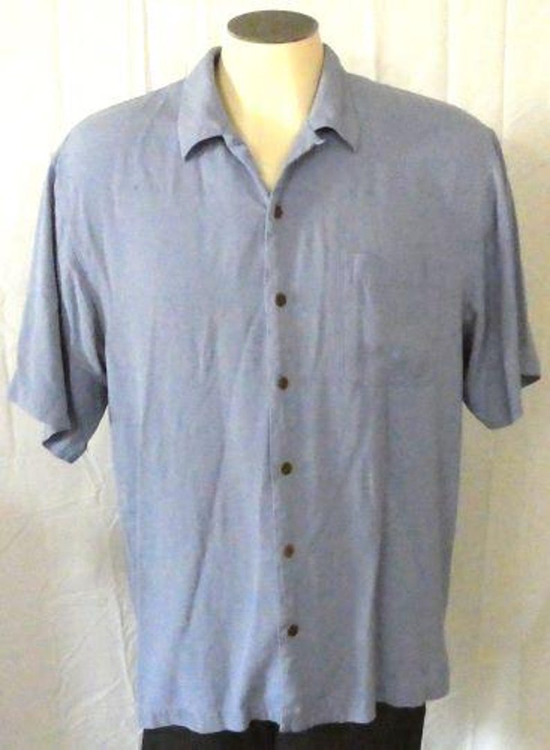 May include: A light blue short-sleeved button-down shirt with a single chest pocket.