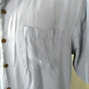 May include: A light blue short-sleeved button-down shirt with a single chest pocket.