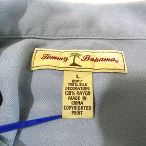 May include: A light blue button-down shirt with a Tommy Bahama label. The label states that the shirt is made of 100% silk and the decoration is 100% rayon. The shirt was made in China.