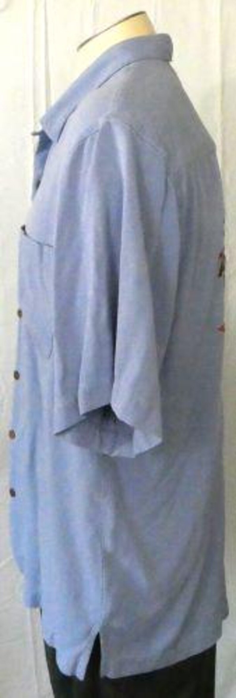 May include: A light blue short-sleeved button-down shirt with a single button cuff. The shirt has a single chest pocket and a collar.