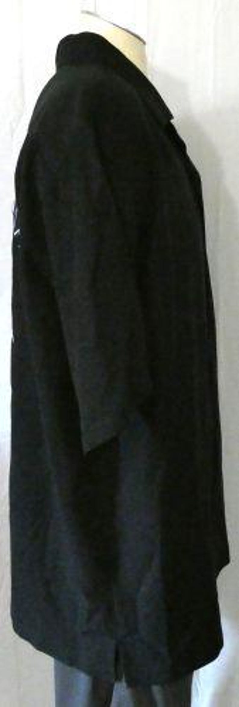 May include: A black overcoat with a notched collar and three-quarter sleeves. The coat is long, reaching below the knees, and has a single vent in the back. The fabric appears to be a medium-weight material, suitable for cooler weather.