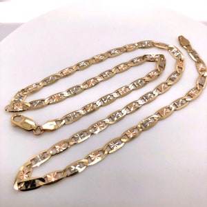 May include: A gold, silver, and rose gold chain necklace with a mariner link design. The chain has a diamond-shaped pattern on each link.