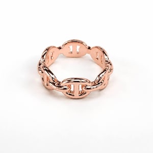 May include: A rose gold ring featuring a continuous chain link design. The band is composed of polished, interlocking oval links, each with a central horizontal bar, creating a uniform, repeating pattern around the entire circumference of the ring.