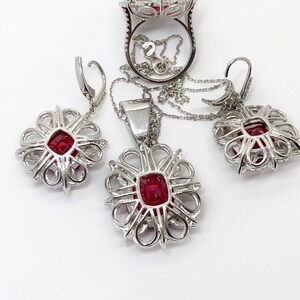 May include: A set of ruby and diamond jewelry featuring a ring, a pendant, and earrings. The pieces are all made of silver and feature a delicate, intricate design.
