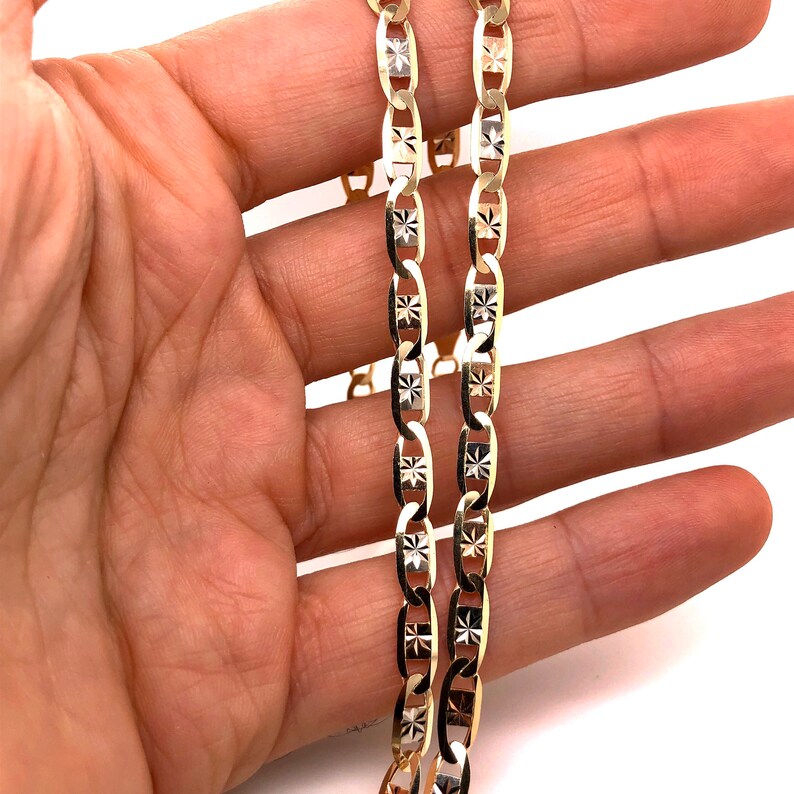 May include: A gold chain necklace with a diamond-cut design. The chain is made of two strands of gold, one with a polished finish and the other with a matte finish.