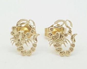 May include: A pair of gold scorpion stud earrings. The earrings are made of 14k gold and feature a detailed scorpion design.