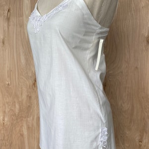 K&ouml;nnte beinhalten: Wei&szlig;es &auml;rmelloses Oberteil mit Spitzenbesatz am Ausschnitt und an den Seiten. Das Oberteil ist aus einem leichten Stoff gefertigt und hat eine lockere Passform.