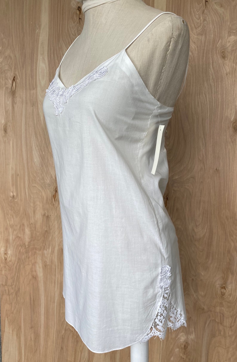 K&ouml;nnte beinhalten: Wei&szlig;es &auml;rmelloses Oberteil mit Spitzenbesatz am Ausschnitt und an den Seiten. Das Oberteil ist aus einem leichten Stoff gefertigt und hat eine lockere Passform.