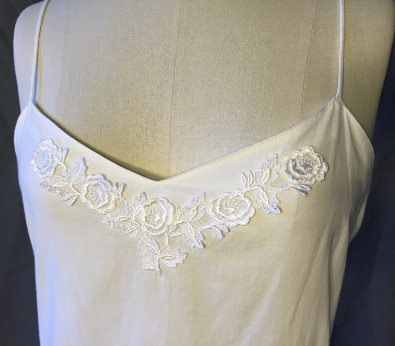 K&ouml;nnte beinhalten: Wei&szlig;es &auml;rmelloses Oberteil mit einer zarten floralen Spitzenborte am Ausschnitt.