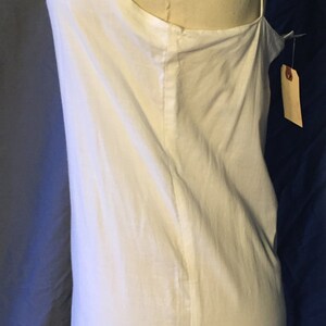 K&ouml;nnte beinhalten: Wei&szlig;es, &auml;rmelloses Schlupfkleid mit einem Spitzenbesatz am Saum. Das Kleid befindet sich auf einer wei&szlig;en Kleiderpuppe.