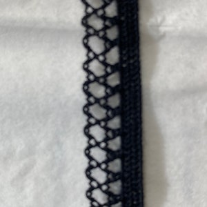 May include: Black lace trim with a delicate pattern. This trim is perfect for adding a touch of elegance to any project.