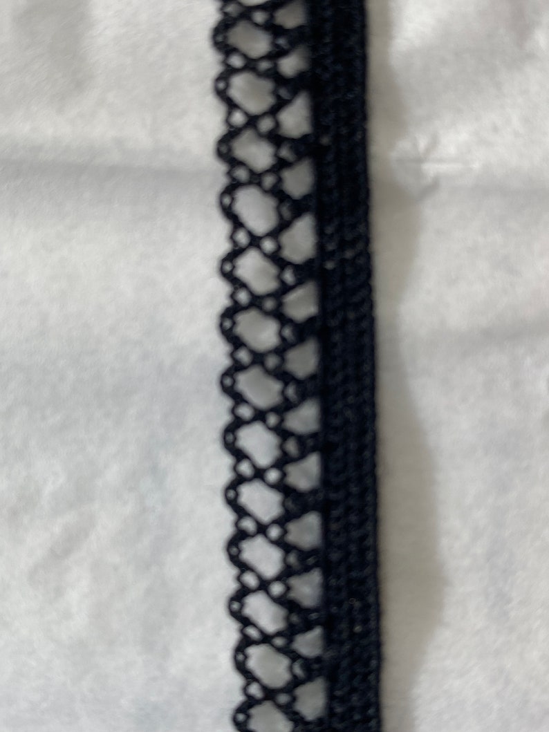 May include: Black lace trim with a delicate pattern. This trim is perfect for adding a touch of elegance to any project.