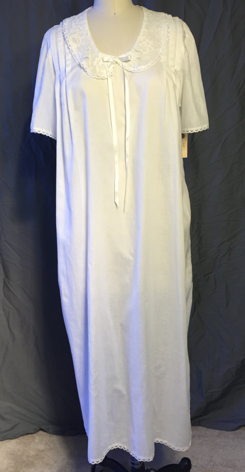 May include: White cotton nightgown with a lace collar and short sleeves. The gown has a satin ribbon tied at the neck.