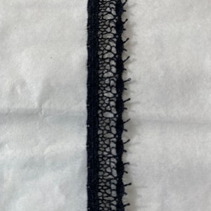 May include: Black lace trim with a delicate pattern. This trim is perfect for adding a touch of elegance to any project.