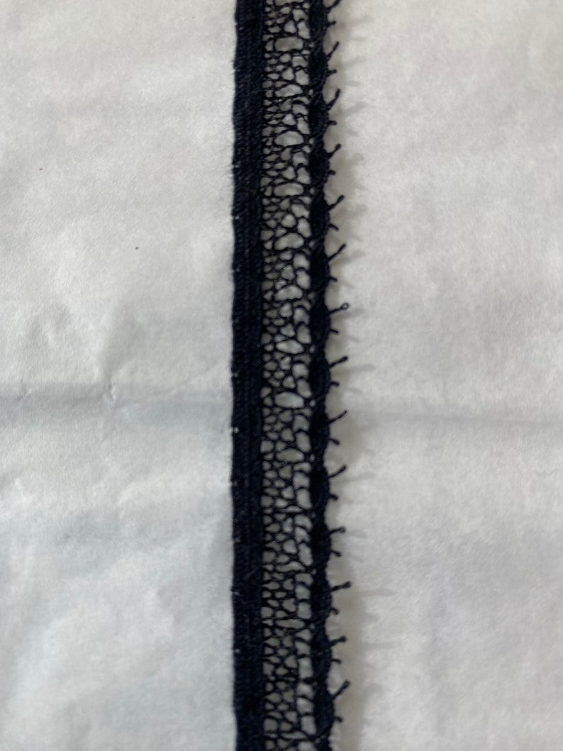 May include: Black lace trim with a delicate pattern. This trim is perfect for adding a touch of elegance to any project.