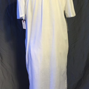 May include: White cotton nightgown with a lace trim around the neckline and sleeves. The nightgown has a button-up front and a straight silhouette.