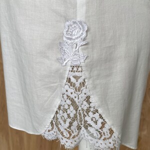 K&ouml;nnte beinhalten: Wei&szlig;er Baumwollrock mit Spitzenbesatz und einer wei&szlig;en gestickten Rose auf der R&uuml;ckseite.
