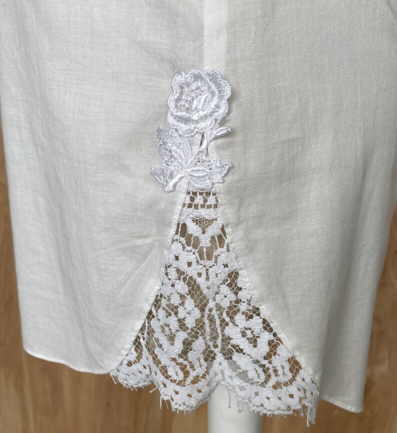 K&ouml;nnte beinhalten: Wei&szlig;er Baumwollrock mit Spitzenbesatz und einer wei&szlig;en gestickten Rose auf der R&uuml;ckseite.