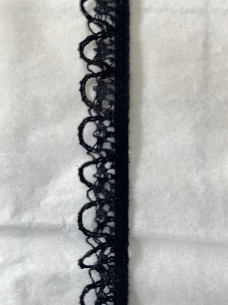 May include: Black lace trim with a scalloped edge.