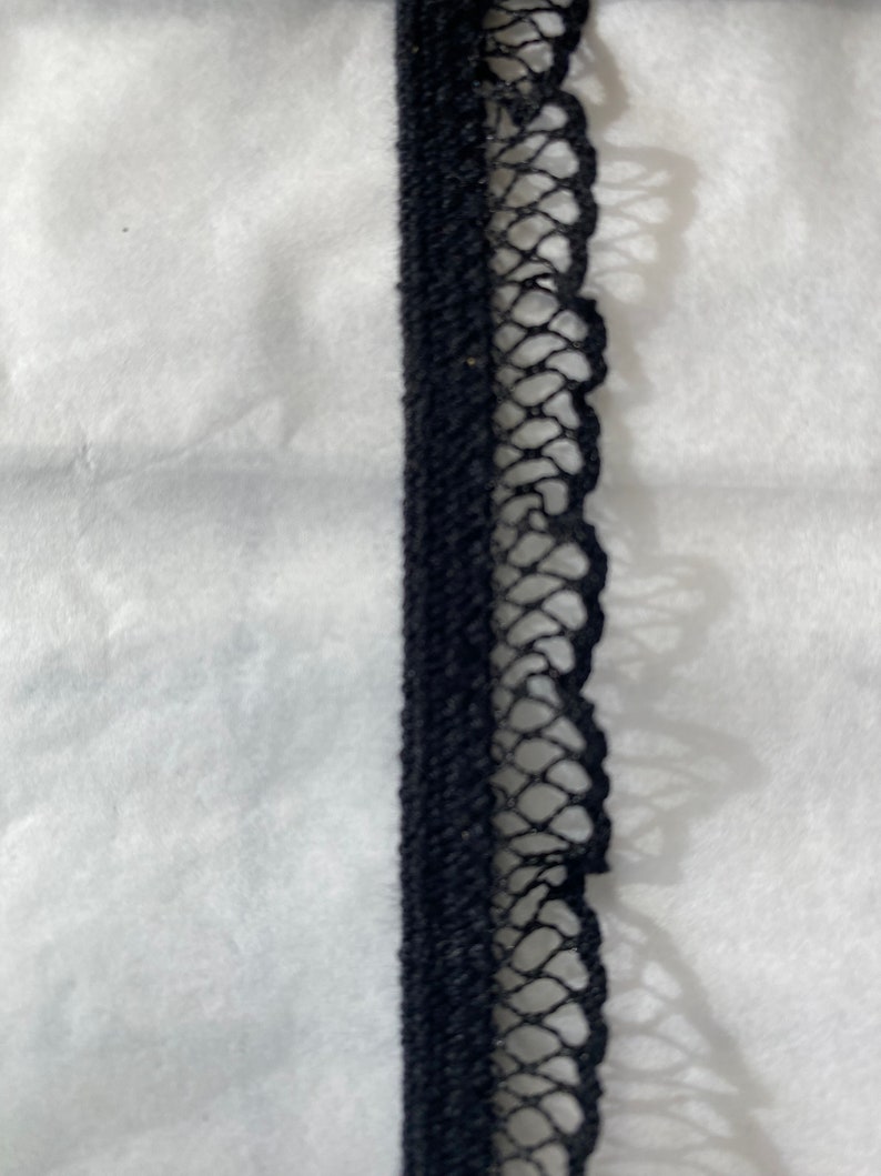 May include: Black elastic trim with a delicate lace edging. The lace is a fine mesh with a scalloped edge.