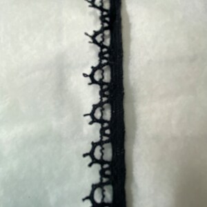 May include: Black lace trim with a delicate pattern. This trim is perfect for adding a touch of elegance to any project.
