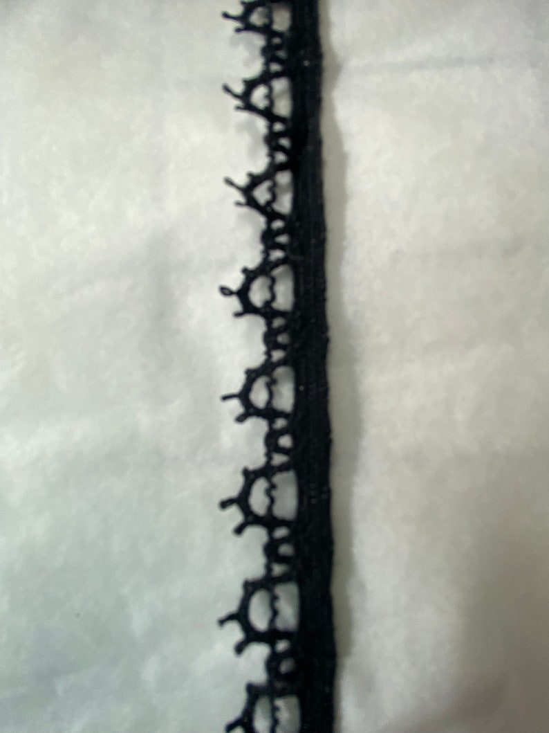 May include: Black lace trim with a delicate pattern. This trim is perfect for adding a touch of elegance to any project.