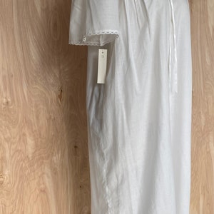 May include: White cotton nightgown with lace trim and a tie at the neck. The nightgown has a tag that says "L" on it.